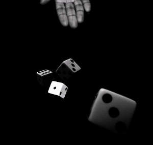 hand throwing a pair of dice in black and white anya brewley schultheiss